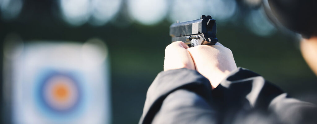 Someone firing a pistol at a target on a shooting range